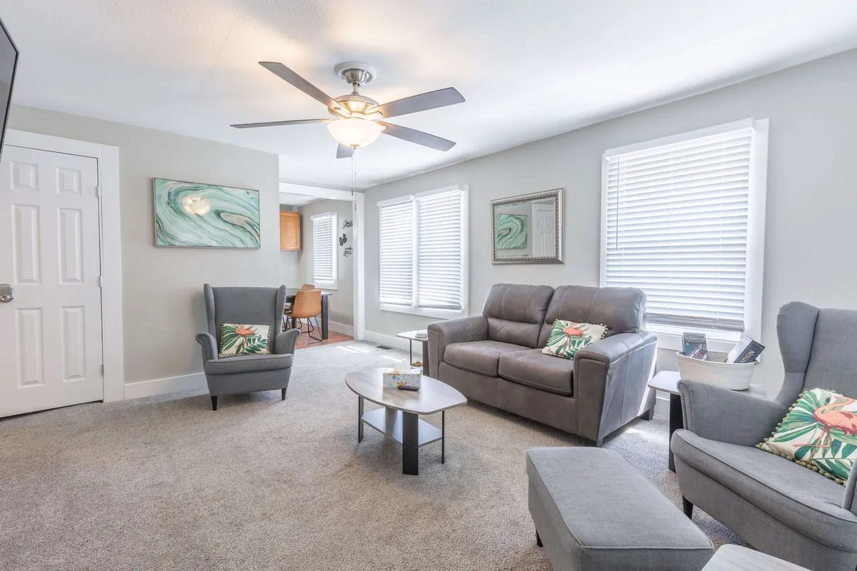 A welcoming living room arrangement with a sofa, armchairs, coffee table, and stylish artwork. The setup is intimate and versatile—great for game nights, coffee chats, or sharing stories, all under soft, natural lighting.