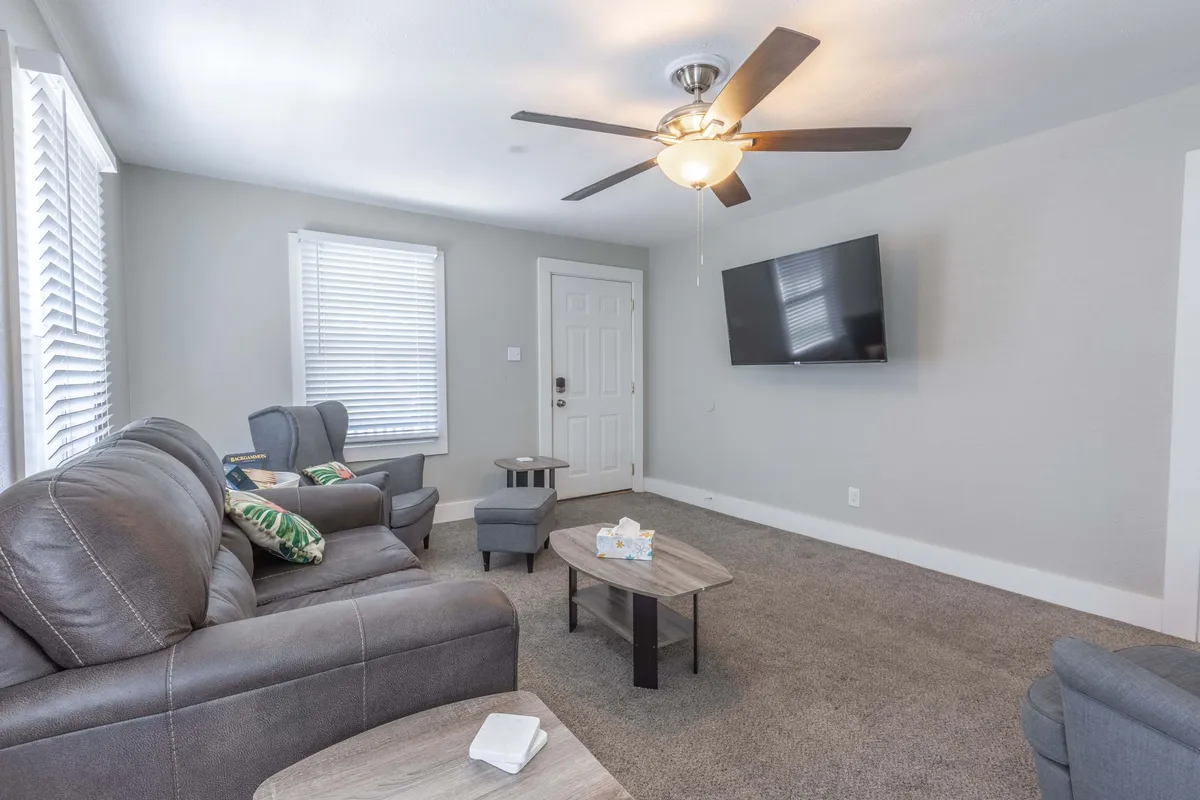 A cozy living area with a soft sofa, coffee table, and TV, complemented by a modern light fixture. The scene is set for movie nights or quiet reading, exemplifying togetherness and relaxation. The lighting and décor establish a warm, welcoming mood.