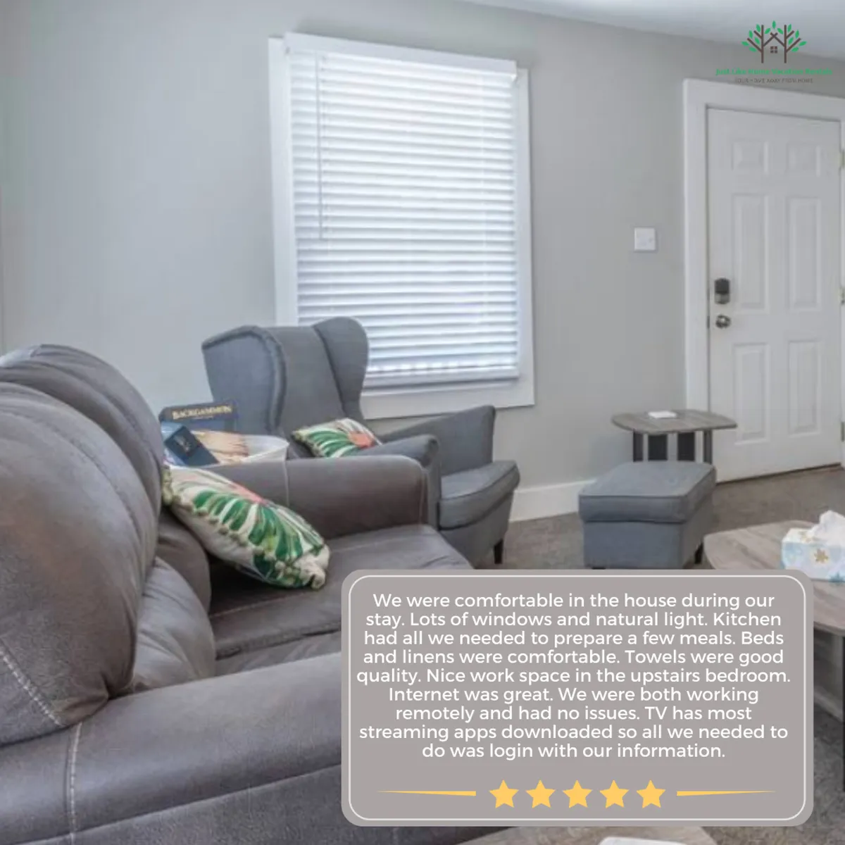 A bright, open living room featuring a comfortable grey couch, stylish chairs, and large windows that flood the space with natural light. Decorative pillows with tropical patterns add a cheerful touch, and the arrangement encourages conversation and relaxation.